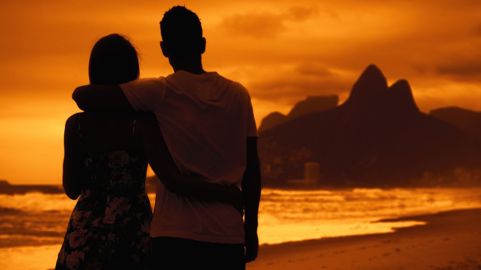 Pareja mira el atardecer en Rio de Janeiro.