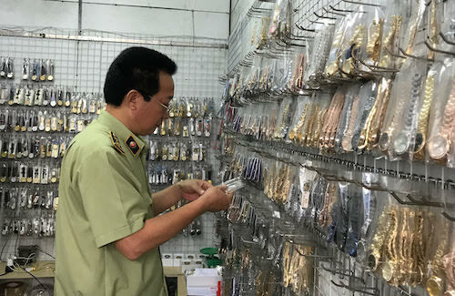 Cán bộ quản lý thị trường kiểm tra đồng hồ giả thương hiệu nước ngoài bán tại chợ Ninh Hiệp (Hà Nội). Ảnh: DMS
