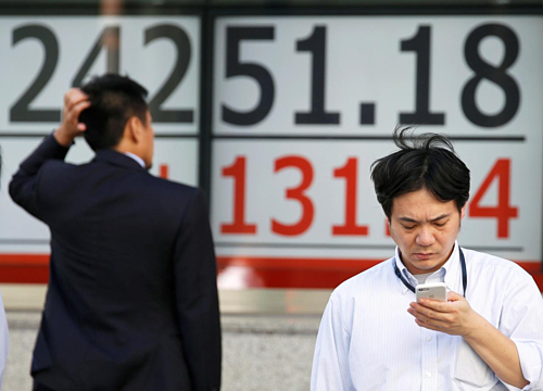 Một người đàn ông xem bảng điện tử bên ngoài một công ty môi giới chứng khoán ở Tokyo. Ảnh: Reuters
