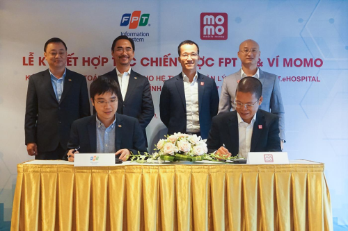 Ông Nguyễn Hoàng Minh, Tổng giám đốc Công ty Hệ thống Thông tin FPT (ngồi bên trái) và ông Phạm Thành Đức, Tổng giám đốc Ví MoMo (ngồi bên phải) ký kết hợp tác chiến lược.