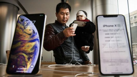 A Chinese man holds his son as they look at iPhones on display at an Apple store on January 7, 2019 in Beijing, China.