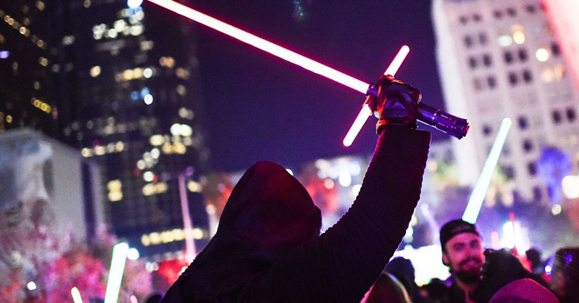 A Star Wars fan dressed as Kylo Ren raises his lightsaber