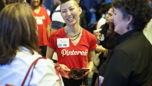 A Pinterest employee speaks with attendees during a Pinterest media event at the company