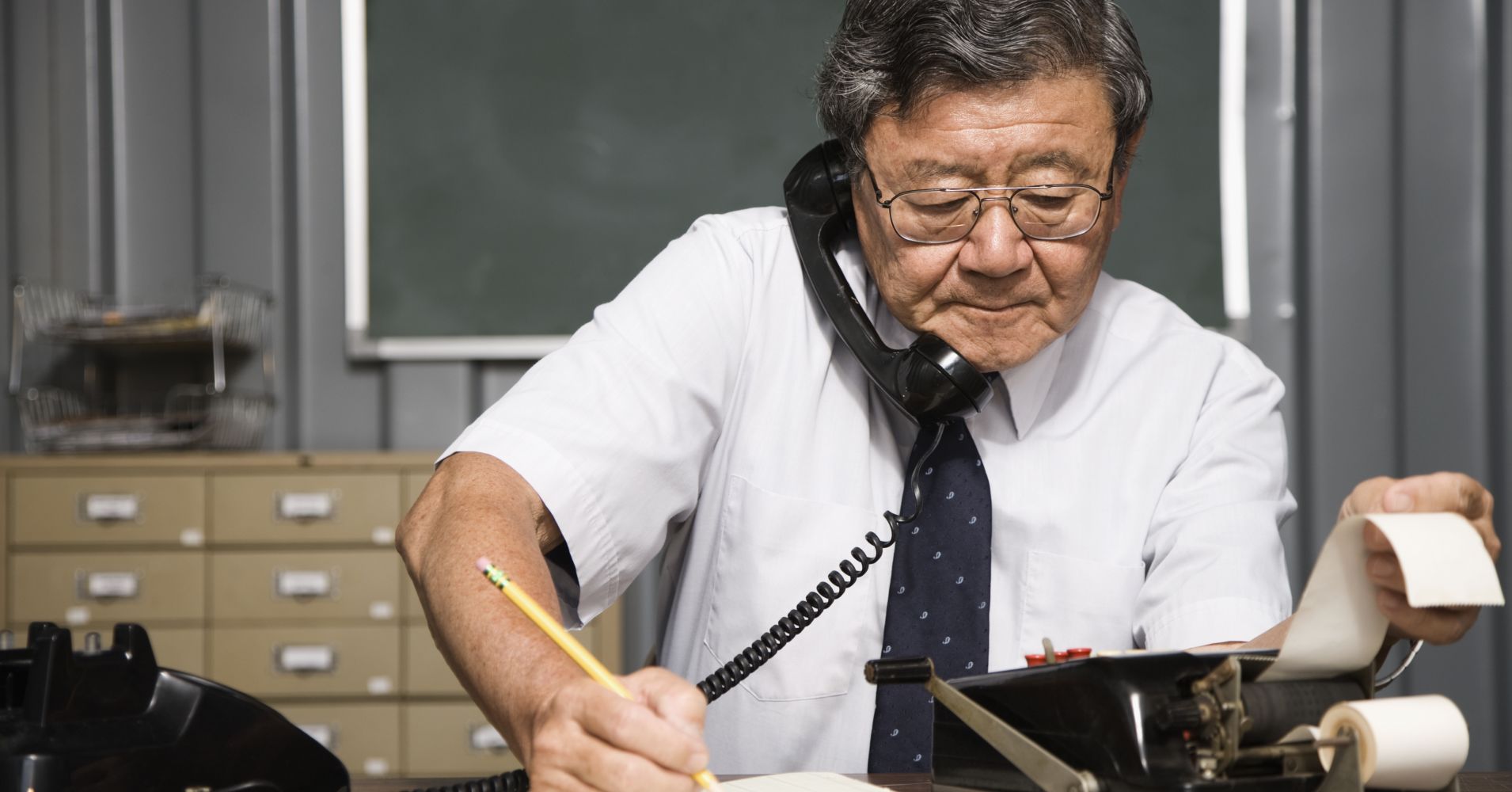 Senior Asian businessman using old fashioned adding machine